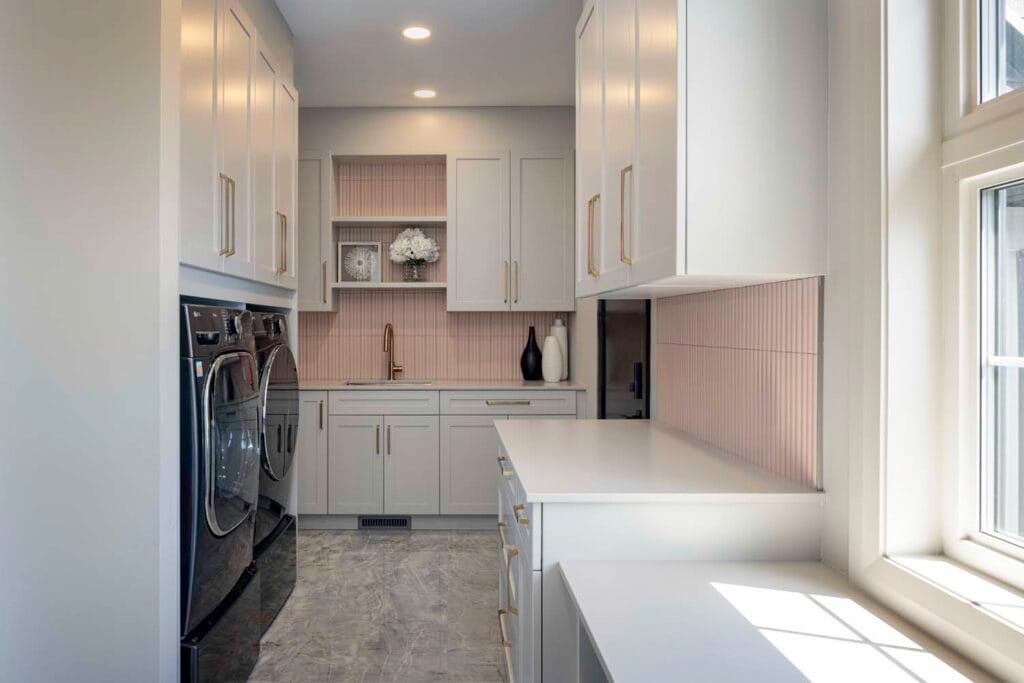 Laundry room design in the Stone Design Concepts Gallery with white cabinetry, natural light from windows, and efficient storage solutions.