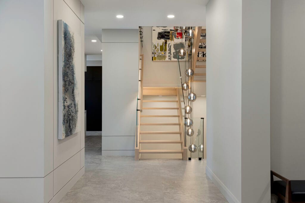 Elegant staircase in Stone Design Concepts Gallery, with natural wood steps, sleek glass railings, and ambient lighting.