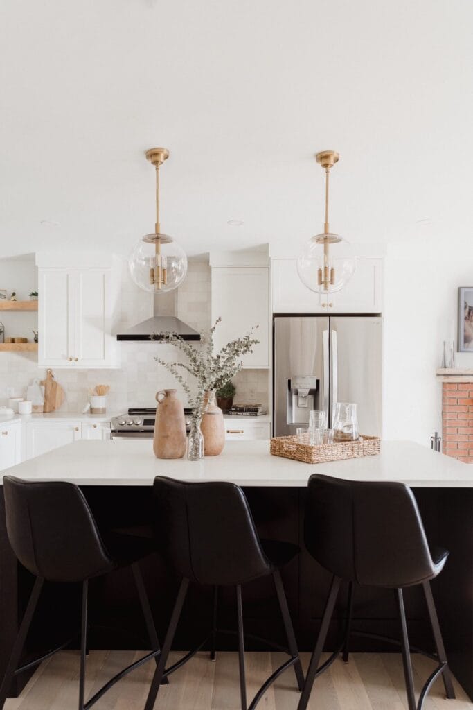 Kitchen island in the Stone Design Concepts Gallery, featuring black stools, pendant lights, and an arrangement of decorative vases.